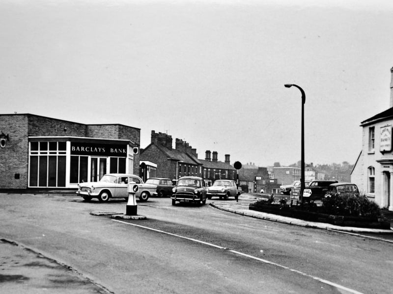 Classic motor cars trundle past the junction of King Street and High Street in Dawley in this nostalgic street scene from the late 1960s. Standing prominently on the right is the Lord Hill public house, while the modern brick front of Barclays Bank anchors the left. Just in the distance along King Street, beyond where the Royal Cinema stood, the multi-storey residential flats built in 1964 peek over the skyline, marking the subtle dawn of the New Town era in East Shropshire. Do you remember visiting Barclays Bank or popping into the Lord Hill pub on Dawley High Street back in the 1960s?