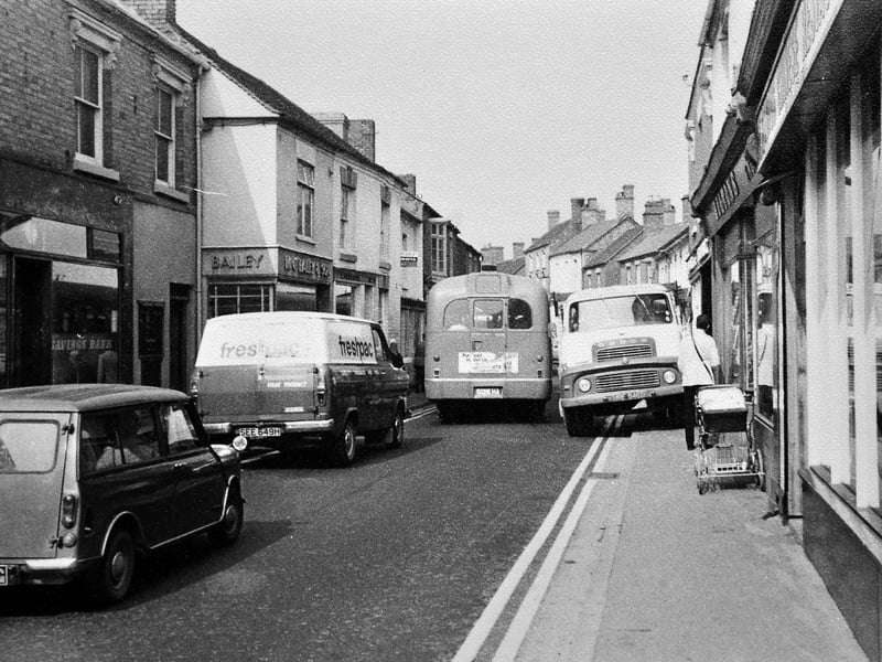 A Midland Red bus is pictured squeezing through Dawley High Street in the 1970s, highlighting how narrow the road once was before any bypass was built. The image, supplied by former bus driver Terry Humphries, shows a busy street scene with a Dodge lorry and a pram also visible. Terry recalls the bus as likely an S17 operating on the 909 route to Wellington, noting just how tight the conditions were for traffic in the town centre at the time