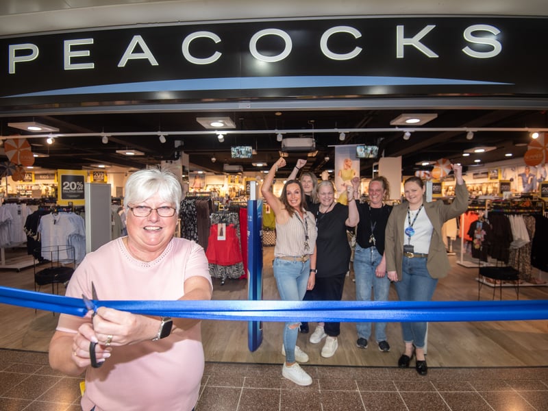 Peacocks store manager Karen Williams cuts the ribbon with staff