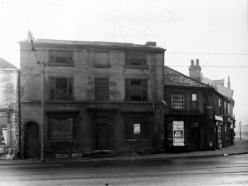 The derelict White Horse Hotel, awaiting demolition. The upper windows are broken, and the lower ones are boarded up. On the right is a bill posted for the Empire Theatre's production of the pantomime Humpty Dumpty. Pictured in December 1952.