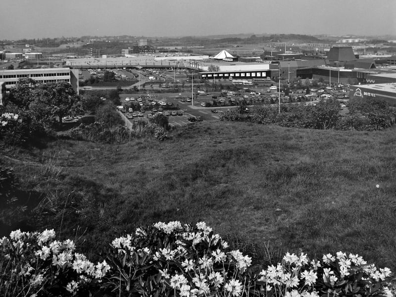 Telford town centre in 1988 is captured in a sweeping panorama, an image that reflects the planned heart of the new town in full flow. From left to right, Malinslee House—home to Wrekin District Council—stands alongside Marks & Spencer, the bus station with its bustle of arrivals and departures, and the surrounding town centre shops. Phase 2 of the development unfolds further along, with W H Smith and Do It All on the right.