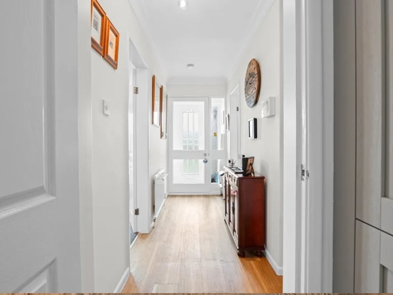 A welcoming hallway on the ground floor branches off into the kitchen, primary bedroom and feature living room, with another bedroom and the bathroom around the corner.