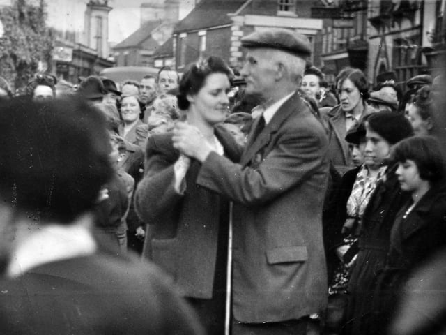 A joyful VE Day scene in Market Drayton, where celebrations spill out into the streets beneath the ivy-clad Corbet Arms on the left of the picture. The photograph was shared by Jackie Smith, who confirmed that the woman pictured dancing was her mother, Gertie Evans. The man dancing alongside her was known locally as William “Uncle Will” Brasenell.