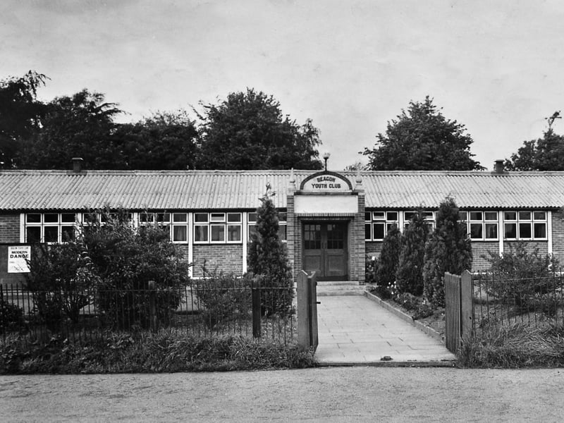 A nostalgic view of the Beacon Youth Club in Market Drayton, believed to date from the 1950s or 1960s when the building was still relatively new. A poster advertising a "Modern Dance" can be seen on the far left, hinting at the social events that made the club such a popular gathering place for local young people. The Beacon Youth Club headquarters opened on September 23, 1948, and later became the Beacon Community Centre, remaining a well-known part of community life in the town.