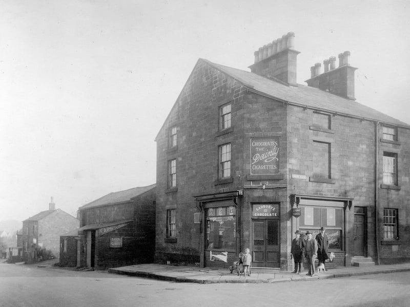 Weetwood Lane, left, at the junction with Moor Road. The shop on the corner was previously 'The Flower Box', owner Alice Greaves. Here it is a confectioners shop with advertisements for Cadburys' chocolate and Lyons cakes. A group of people pose outside the shop. Pictured in October 1930.