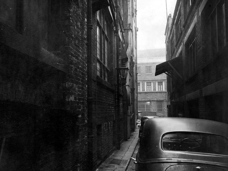 A view down Pack Horse Yard, a narrow alley connecting Briggate and Lands Lane. Cars are parked along it. Pictured in December 1946.