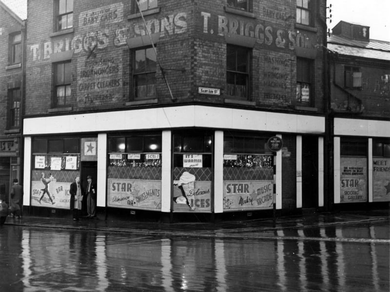 Woodhouse Lane and the junction with St. Anns Street in November 1946. Upper walls painted with information of previous use of premises: Thomas Briggs, ironmonger, brass and iron bedstead manufacturer. Now "Star" amusement arcade. Three men on left, one wearing bowler, two in "Star" doorway.