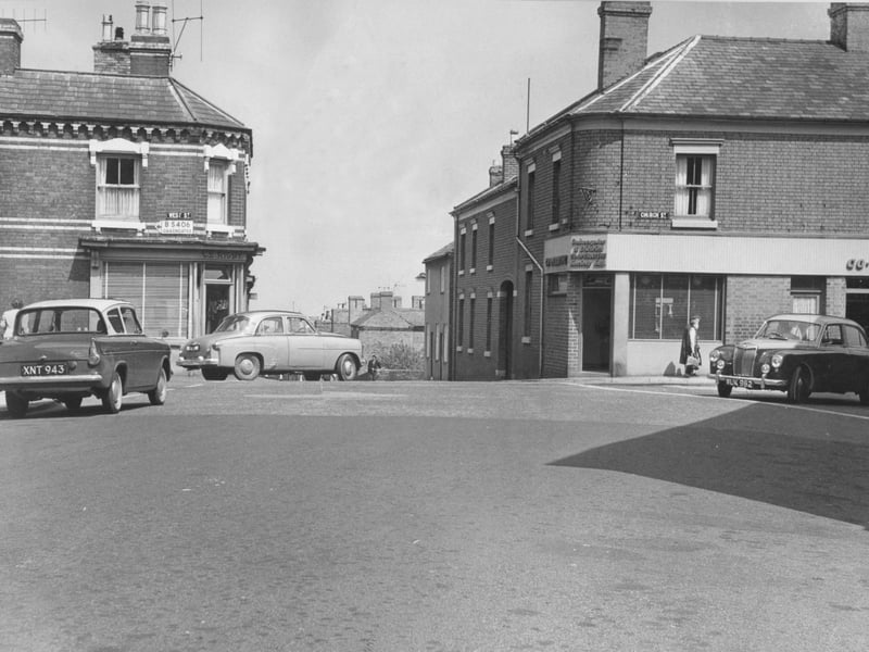 A view of St Georges crossroads on 18 July 1962, capturing a busy junction that was already known locally as an accident blackspot. On the left, along West Street, stands the C E Rigby store, while the Co-operative store occupies the corner of Church Street opposite. Old cars pass through the scene as traffic flows across the junction, at a time when the introduction of traffic lights was being considered.