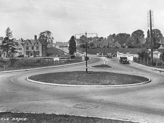 A view of Meole Brace in Shrewsbury, showing the traffic island and the Brooklands Hotel, set against the newly established bypass opened in 1933. Likely dating from the mid-20th century, the scene captures an early era of motoring, with period cars navigating the roundabout at what was becoming an important junction on the edge of town.