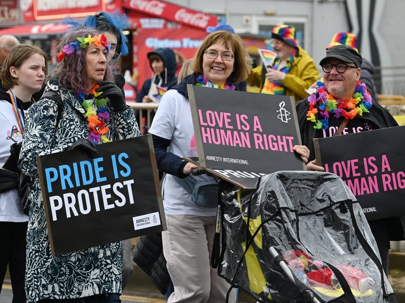 Participants at Blackpool Pride 2026 hold signs reading “Love is a human right” and “Pride is protest” during the event.