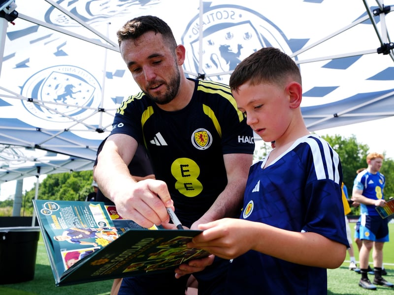 Scotland's John McGinn (left) signs autographs for a fan