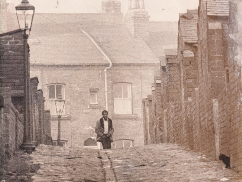 A black cat peeks out as a man walks though the soon to be demolished streets of Little London in February 1973.