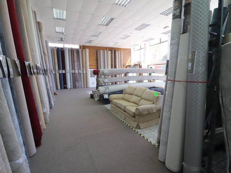 While one side of the store sells second hand furniture the other stocks new carpets.
