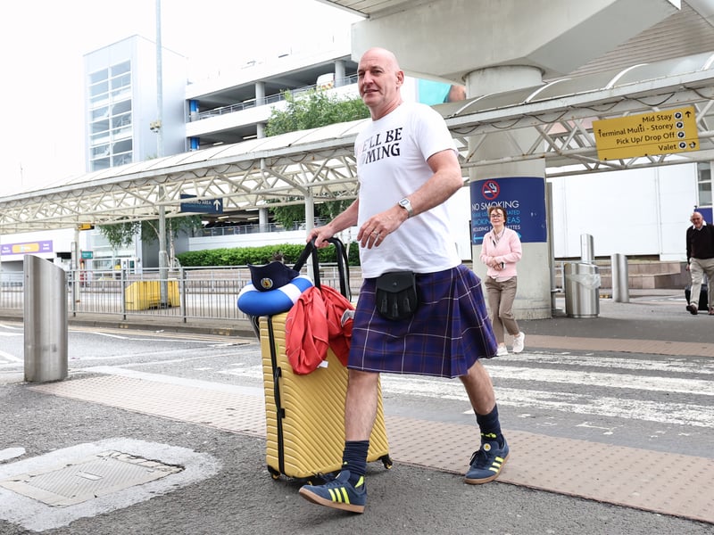 A kilted Scotland fans head to the departures lounge to take off to the United States for the World Cup.