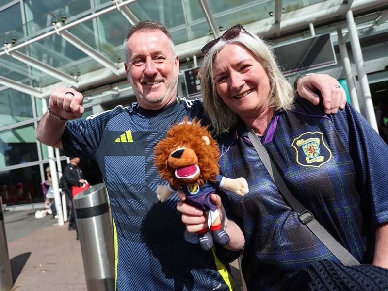 Two Scotland fans pose for a photo ahead of their flight to the United States at Edinburgh Airport.