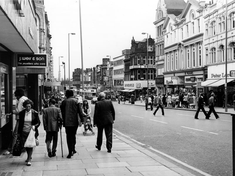 Briggate thronged with shoppers in April 197. On the left is J.Weir & Son 'the jeweller's who care' and further down, Debenhams. On the right, Dolcies shoe shop is visible on the corner with Albion Place, then Hornes and Hepworths followed by the Army Stores and Peter Lord's far right.
