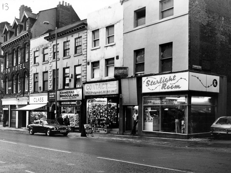Looking west at shops on Lower Briggate. On the left is the Golden Lion Hotel by the junction with Swinegate, then No.3 is Class menswear, No.4 Bass and Bligh, camera and binocular repairs, No.5 Contact second hand goods and No.6 Starlight Room amusements. On the right is the junction with Heaton's Court. Pictured in December 1979.
