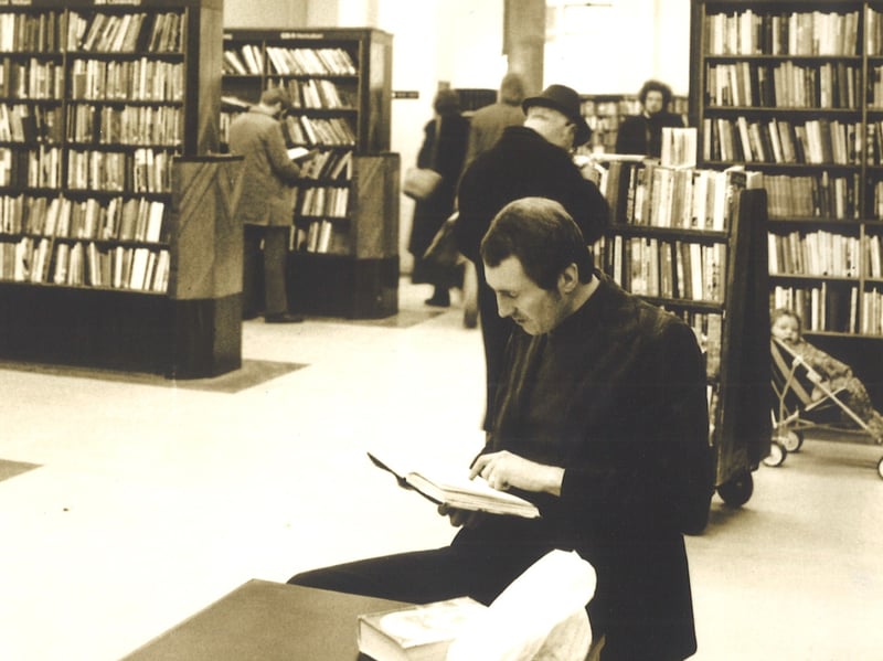 A view is looking north across the Central Lending Library, on the ground floor of Leeds Central Library. The windows in the background front onto Alexander Street. Library customers are browsing shelves and a gentleman is seated in the foreground reading a book. Pictured circa 1977.