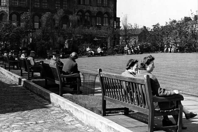 Looking south at the rest garden on Merrion Street. People sit on park benches arranged around a central square lawn. Behind is L. & M. Dombyack, furriers, at number 35 Wade Lane. Pictured in September 1943.