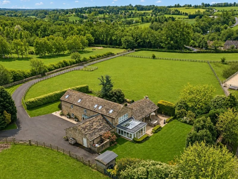 This lovely four-bedroom barn conversion is set in nearly four acres of land. The generous family home blends modern fittings with charming traditional features, like the exposed beams and striking barn windows. As well as two reception rooms and a home office, it boasts a stunning orangery with doors to the garden.
