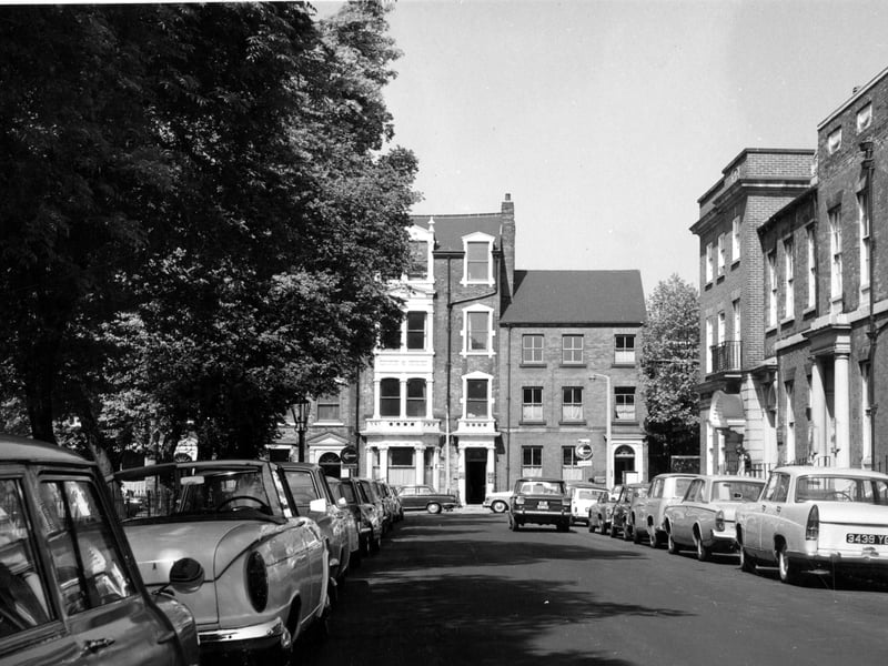 Park Square. Cars are parked on both sides of the road. The trees are in full leaf.