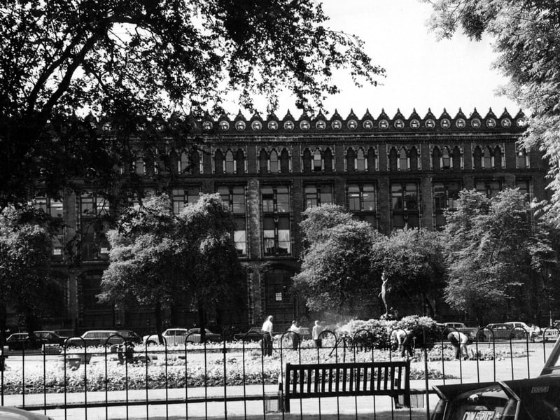 Park Square. A statue of Circe can be seen in the garden. Men working in the garden are also visible and there are parked cars in the street.