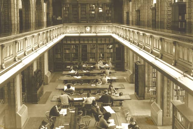 Looking from the gallery down to the Reference Library on the second floor of Leeds Central Library. This room is on the south side of the building and fronts onto The Headrow. Many people are seated at the long desks studying or reading.