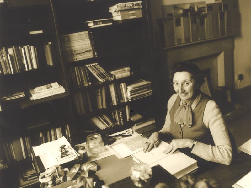 Library staff member Annie Hinchcliffe seated at a desk and carrying out some work on books before they are shelved. This is in a room on the second floor corridor of Leeds Central Library, now known as the Gott Room.