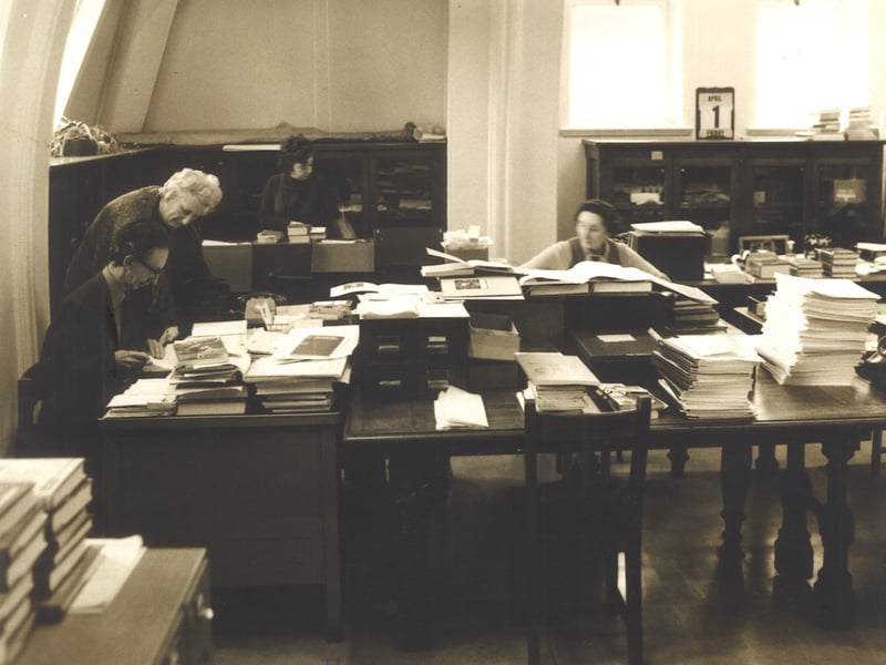 Staff at desks in the Books Acquisitions Department of Leeds Central Library. This is on the third floor of the library in the north west corner and is now known as the Sanderson Room. From left are Geoff Barratt, Marion Hartley, Barbara Hopper and Annie Hinchcliffe.