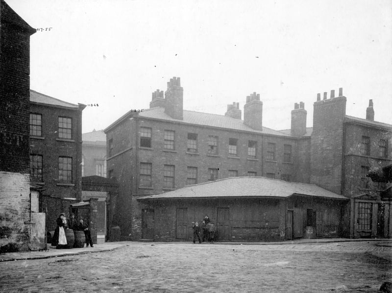 The arched entrance to south Market off Meadow Lane in May 1900. On the left a group of people are posing around some beer barrels, which presumably were for the Ann Ellen Ambler owned South Market Hotel, which is behind them.