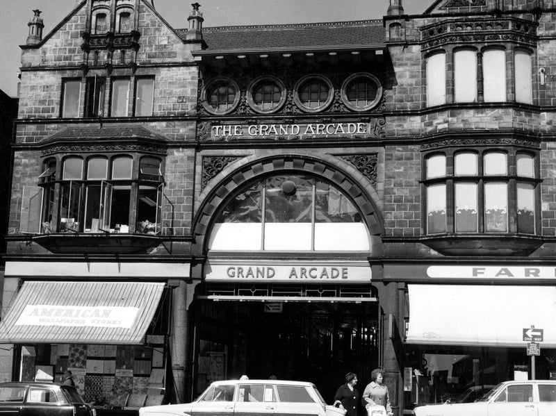 The entrance to Grand Arcade on Vicar Lane. Shops on either side, both with awnings. On the left is the American Wallpaper Stores.