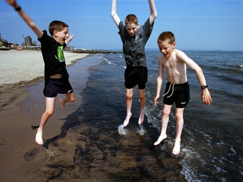 Twins Gordon and Stuart MacDougall and brother Angus play in the waves at sunny Portobello in June 1998.