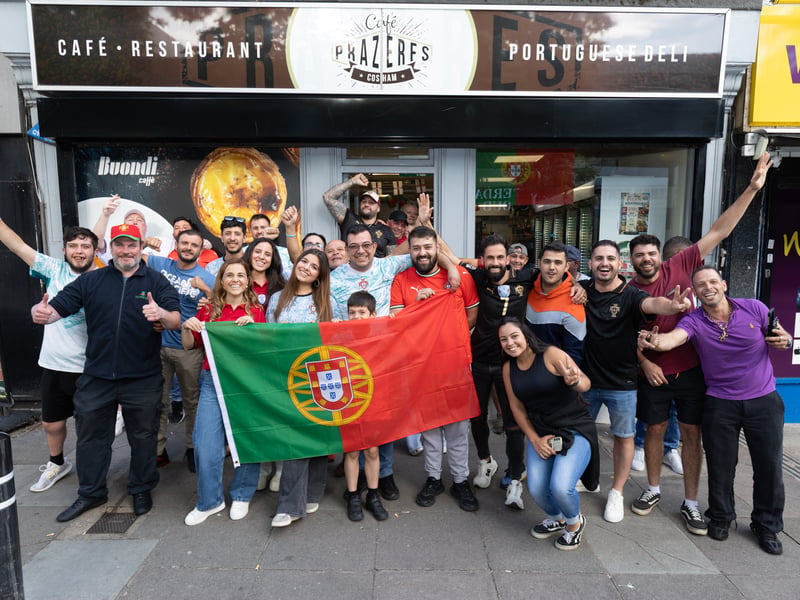 Portugal supporters outside Cafe Prazeres during Portugal's opening game of the World Cup on Wednesday, June 17. Janete Bichinho, Pedro Bichinho and Daniel De Freitas are holding the Portuguese flag.