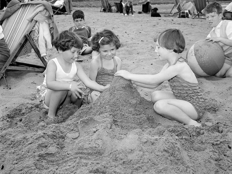 Three girls building a sandcastle on Cramond Beach in summer 1954.