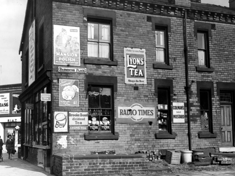 Looking north east at number 94, Roundhay Road, on the corner of Badminton Place. There is a General Grocer's shop, with adverts for Lyon's Tea, Mansion Polish, Radio Times and Colman's Mustard. There are two women to the left of the photo, one pushing a pram. Pictured in September 1953.