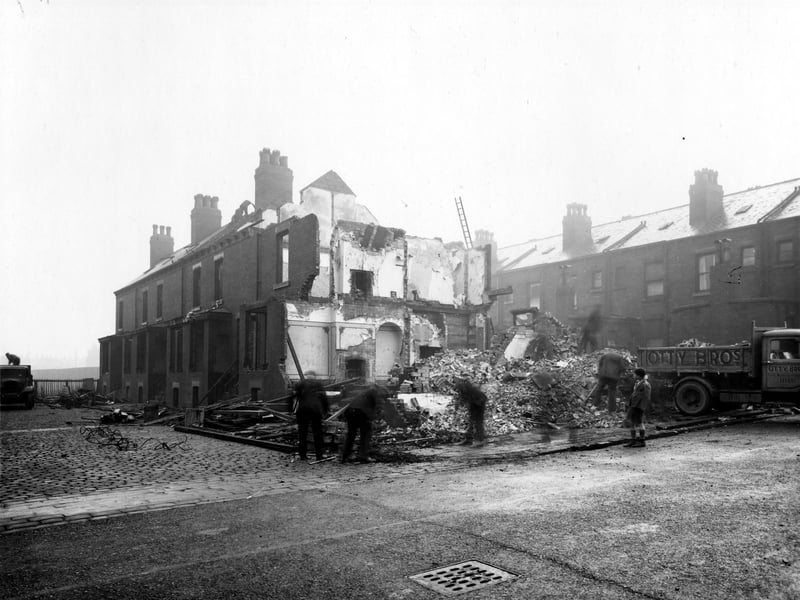 Walford Avenue, located off York Road, at the end of Nickleby Road, property under going demolition. End wall has pattern of rooms, fireplaces and floors. Workmen are dealing with debris, a lorry is on the right being loaded with rubble. It belongs to Otty Brothers, painted on the door 'Public Works Contractor'. Pictured in November 1938.