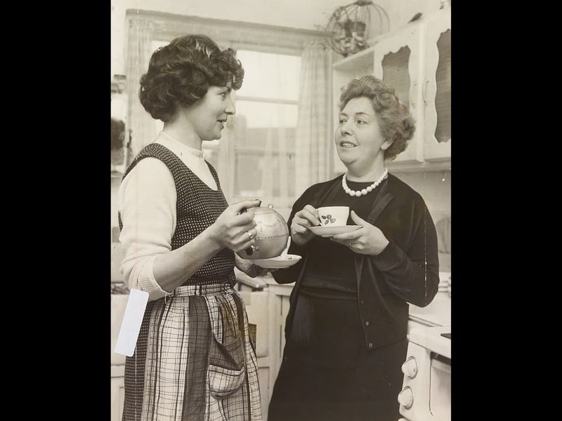 Sisters Lillian Woolley and Louise Palmer pause for a quick, well-earned cup of tea in the busy kitchens of the Civic Hall in May 1962. The duo was part of the hard-working catering team preparing a grand civic luncheon hosted in honour of Her Majesty Queen Elizabeth II during her official visit to the town. The grand menu served to the monarch and local dignitaries featured smoked salmon, chicken, and fresh strawberries with cream, making it an unforgettable day for everyone working tirelessly behind the scenes. Did you or anyone in your family help out behind the scenes for the Queen's royal visit back in 1962?