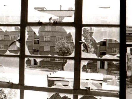 A view looking through a broken window in one block of Quarry Hill Flats (possibly Moynihan House) towards another block (York House). The flats were in the process of demolition at the time when this photo was taken in 1977.