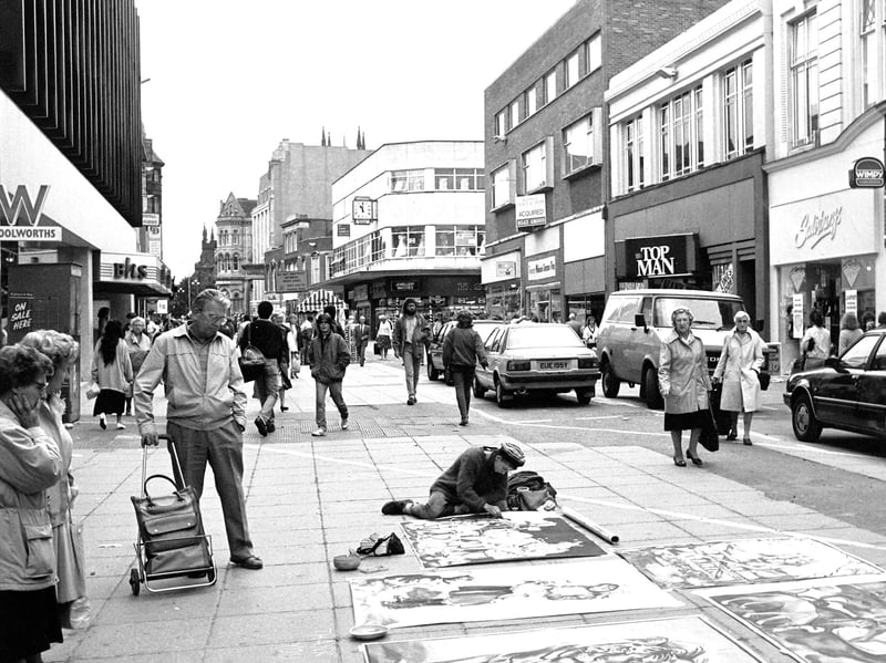 A pavement artist works his magic in Dudley Street, Wolverhampton, in July 1989, attracting the attention of shoppers outside Woolworths. The busy city centre was home to familiar names including Wimpy, Salisburys, Top Man, BHS and H Samuel. Do you remember seeing street artists like this on a day out in town?