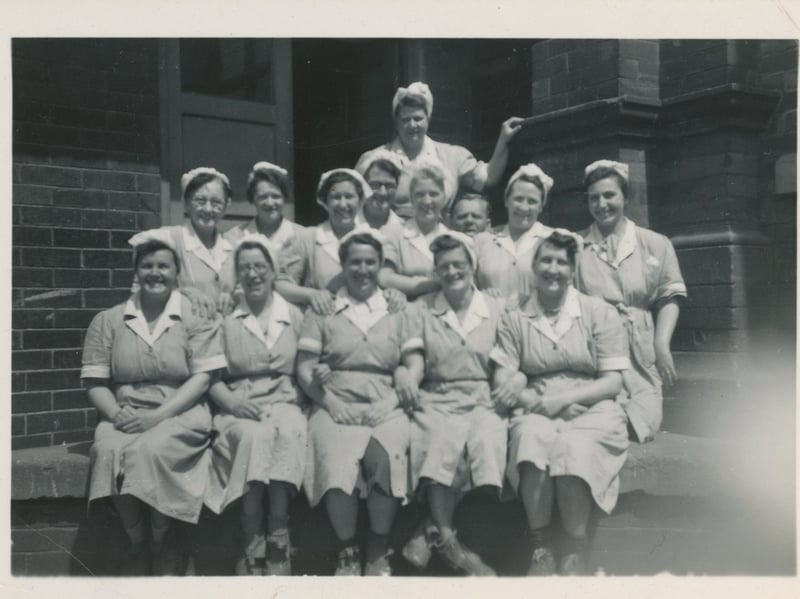 A group of workers from the Quarry Hill Flats canteen cookhouse pose for a photo  circa 1950s in uniform.