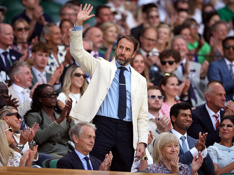 Former England football manager gives the Wimbledon crowd a wave.