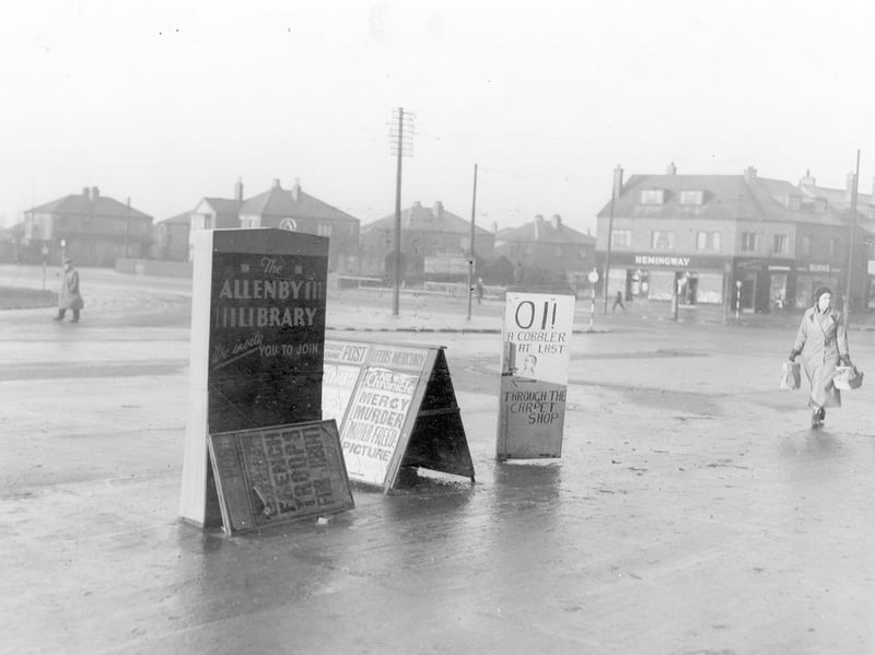 The corner of the Ring Road on the Middleton side of Dewsbury Road pictured in December 1938. Semi detached houses on Waincliffe Mount visible in the distance. A woman with shopping is in the middle ground, plus newspaper placards and Hemingways shop.