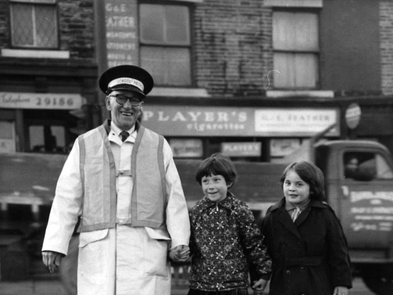 Jack Hague becomes the first Bradford school crossing warden to wear the new fluorescent orange jackets, which will eventually be issued to all wardens in the city, in October 1966. He is pictured on duty at the busy Smiddles Lane junction.