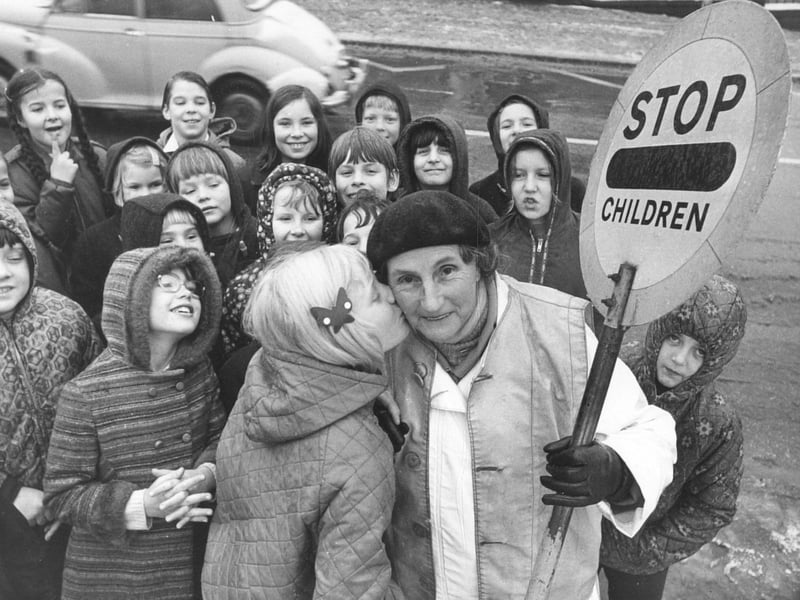 Sally Bowers, aged nine, plants a kiss on the cheek of lollipop lady Mary Thrippleton, aged 70, who has completed 20 years as a lollipop lady outside New Park Primary School, Harrogate, in December 1973