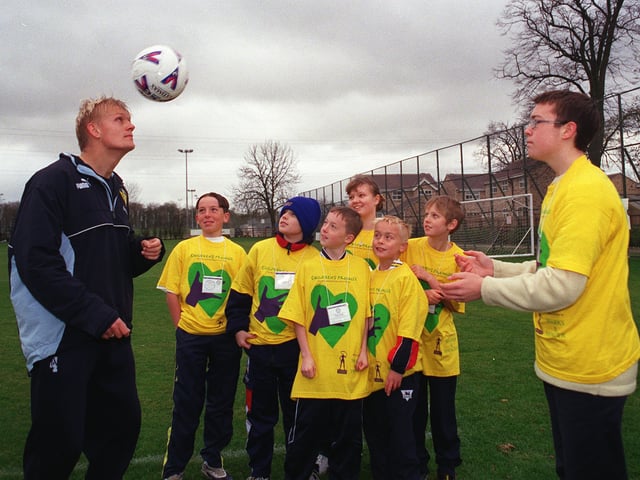 Leeds United footballer Alf-Inge Haaland  heading the ball  thrown by  Sam Illingworth 15  watched by the Marks and Spencer  competition winners , Jessica Rawling 13, Matthew Rawling 12, Paul Robson 13,David Robson 11, Ben Lofthouse 12 and Stuart Williamson 8   at Leeds United's training ground at Thorp Arch , to kick off the  Marks and Spencer  millennium  charity  Children's Promise.