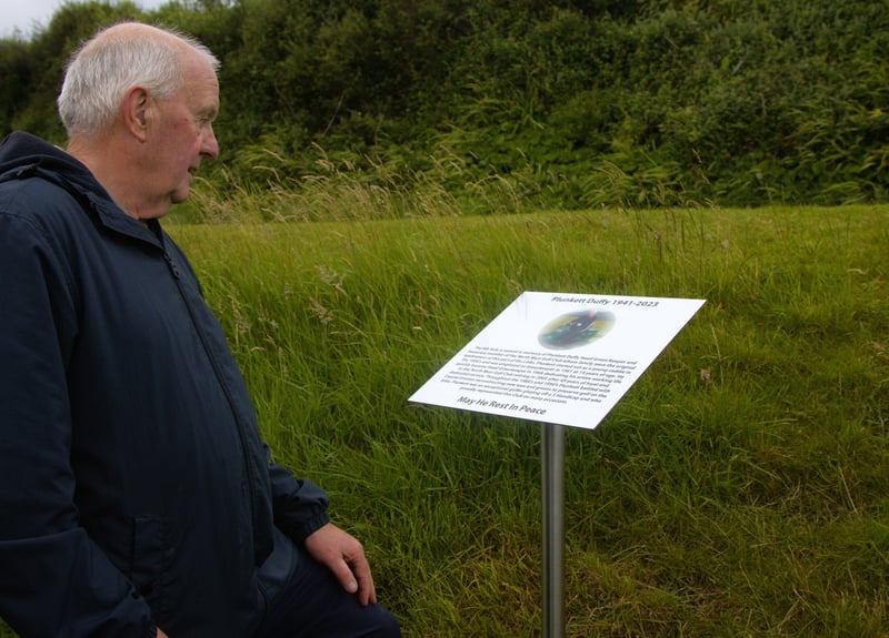Hugh Duffy reading the plaque in memory of the late greenkeeper Plunkett Duffy at NWGC 