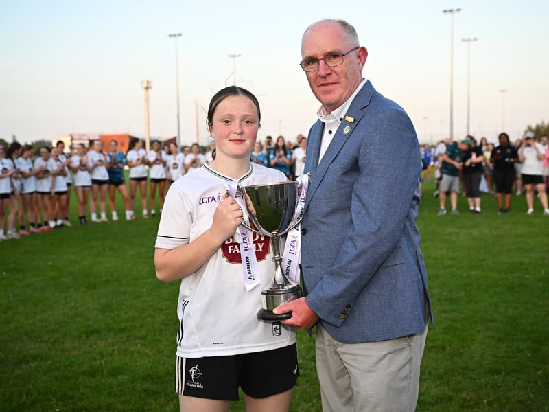 Kildare captain Amy Wall receives the cup from Arthur Corrigan, Leinster LGFA President, after the 2026 AirNav Ireland All-Ireland U-16 A Championship final match between Cavan and Kildare at Páirc Chiarain in Westmeath. Photo by Seb Daly/Sportsfile 