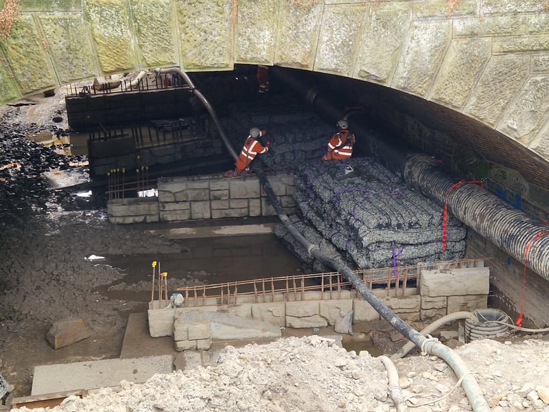 Workers are installing walls in the river bed.