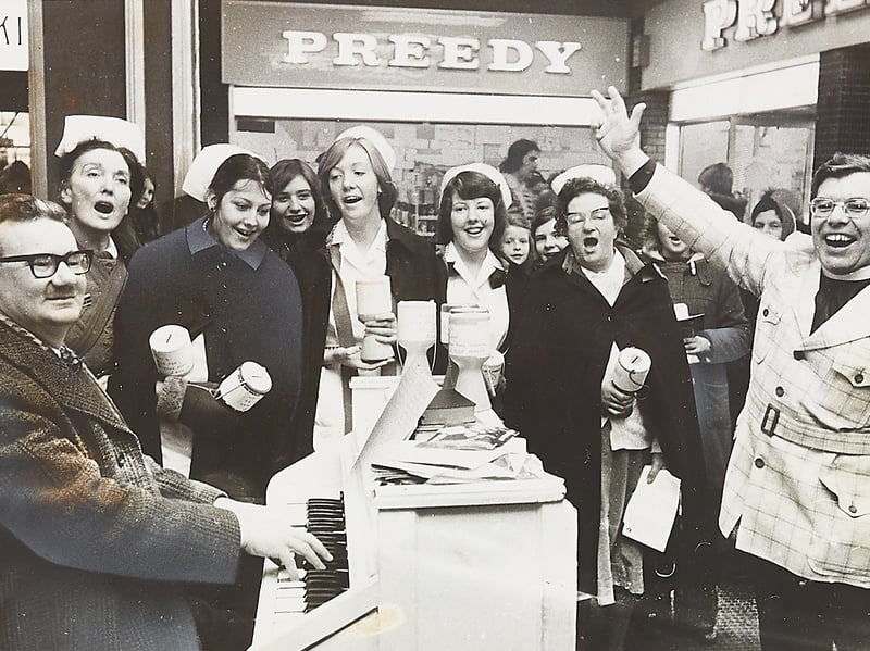 The Rev Eddie Smith enthusiastically conducts as John Grainger plays the keys and local nurses sing out festive carols for shoppers outside Preedy in Dudley's Trident Centre in December 1976. Carrying collection tins while leading the seasonal cheer, the choir held their annual concert to raise funds towards a specialist bed for the geriatric unit at Burton Road Hospital. Did you do your Christmas shopping at the Trident Centre or drop coins into the nurses' collection tins back in the winter of 1976?