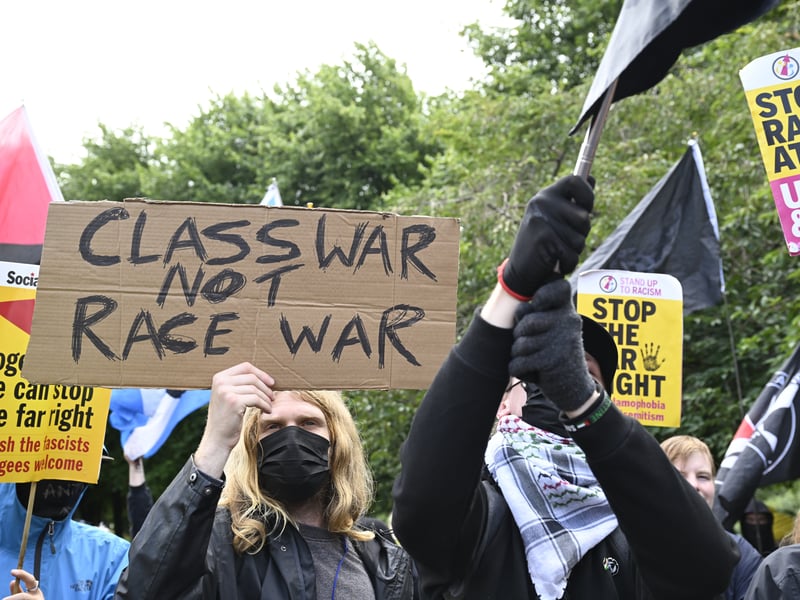 A campaigner holds up a placard stating 'Class War Not Race War' at Glasgow Green.